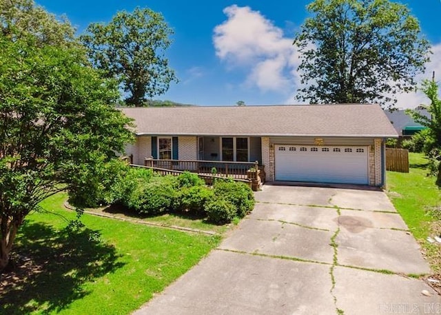 single story home featuring brick siding, concrete driveway, a front yard, a garage, and a porch
