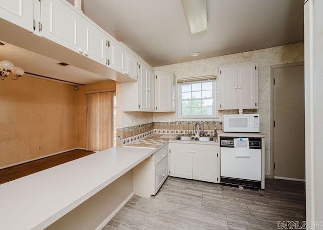 kitchen featuring white appliances, a sink, white cabinets, tasteful backsplash, and light countertops