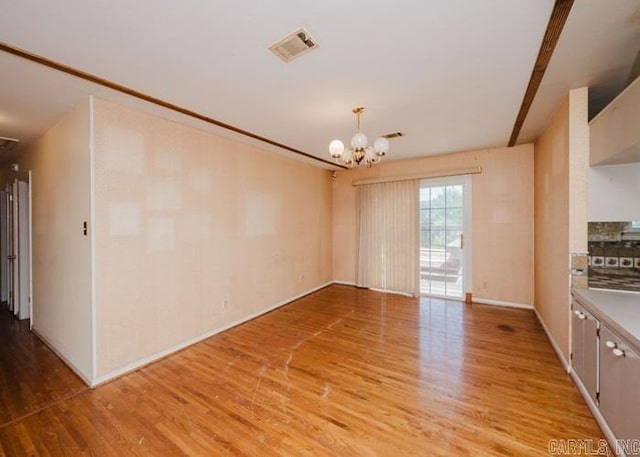 unfurnished room featuring light wood-style flooring, a chandelier, and baseboards