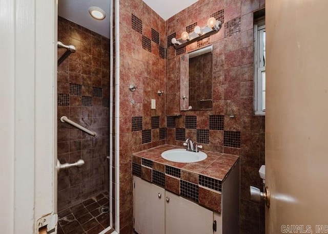 full bath featuring a shower stall, vanity, and tile walls