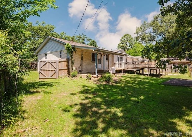 back of house featuring a lawn and a deck
