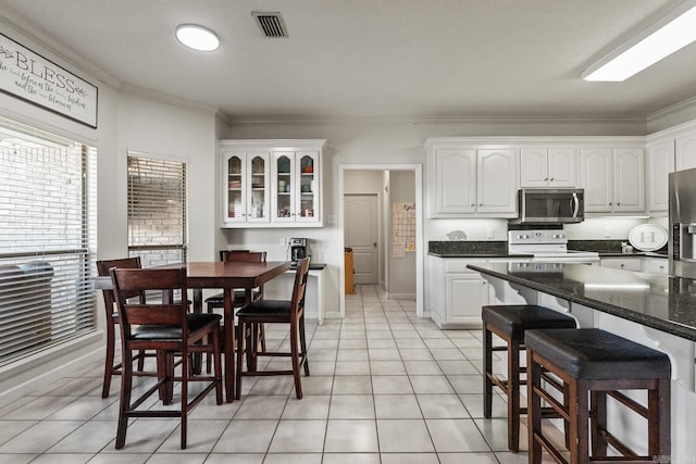 3720 Mcconnell Dr, Conway, AR 72034 - kitchen with stainless steel microwave, white range with electric stovetop, ornamental molding, white cabinetry, and light tile patterned floors