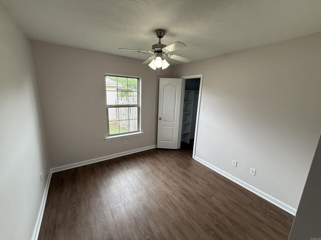 406 Apricot St, Austin, AR 72007 - unfurnished bedroom with dark wood finished floors, baseboards, a walk in closet, ceiling fan, and a closet