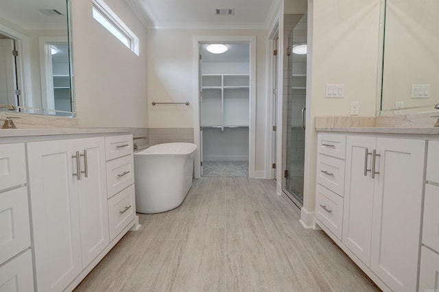 9 Quartz Cv, Little Rock, AR 72223 - bathroom featuring ornamental molding, two vanities, a shower stall, a soaking tub, and a spacious closet