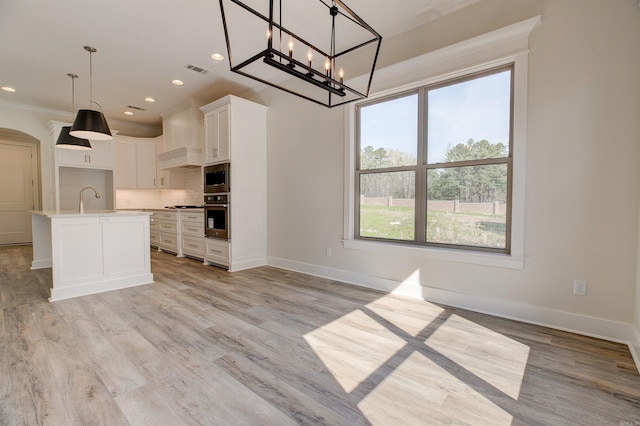 9 Quartz Cv, Little Rock, AR 72223 - kitchen featuring appliances with stainless steel finishes, a chandelier, white cabinetry, arched walkways, and backsplash