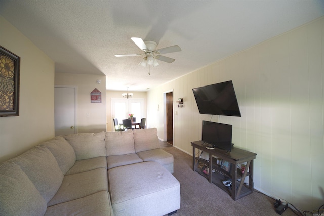 living room with a ceiling fan, a chandelier, carpet flooring, and a textured ceiling
