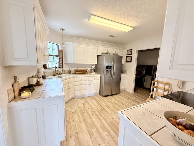 7 Butterfly Dr, Sherwood, AR 72120 - kitchen with stainless steel refrigerator with ice dispenser, a sink, light wood-type flooring, white cabinetry, and tile countertops