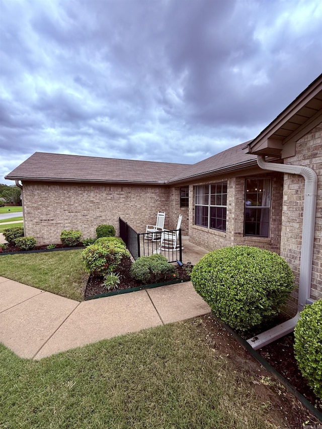 7 Butterfly Dr, Sherwood, AR 72120 - view of property exterior featuring brick siding, a patio, roof with shingles, and a yard