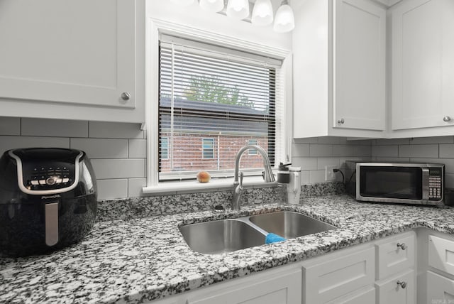 30 Center St Unit A & B, Mayflower, AR 72106 - kitchen with stainless steel microwave, a sink, white cabinets, backsplash, and light stone counters