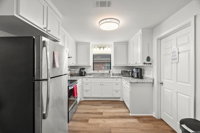 30 Center St Unit A & B, Mayflower, AR 72106 - kitchen featuring appliances with stainless steel finishes, a sink, white cabinets, light wood finished floors, and light stone counters