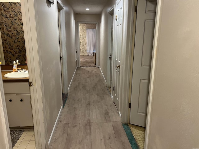 17003 Quail Run Dr, Little Rock, AR 72210 - hallway featuring a sink, light wood-style flooring, and baseboards