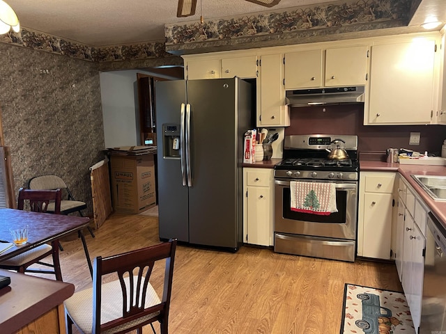 17003 Quail Run Dr, Little Rock, AR 72210 - kitchen featuring stainless steel appliances, under cabinet range hood, light wood finished floors, ceiling fan, and dark countertops