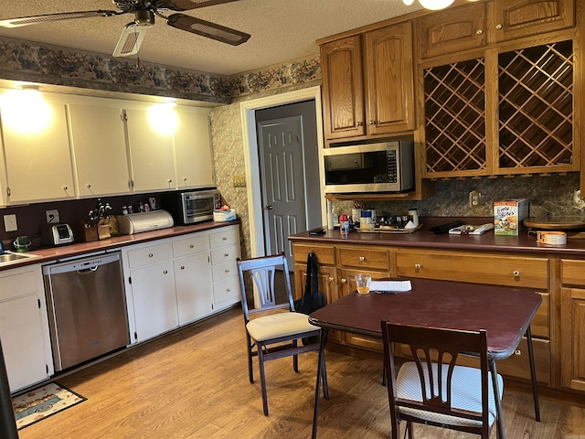 17003 Quail Run Dr, Little Rock, AR 72210 - kitchen featuring appliances with stainless steel finishes, dark countertops, light wood finished floors, white cabinetry, and ceiling fan
