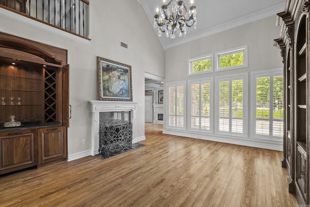 119 Marseille Dr, Maumelle, AR 72113 - unfurnished living room with crown molding, high vaulted ceiling, a chandelier, a high end fireplace, and light wood-style flooring