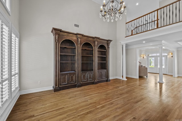 119 Marseille Dr, Maumelle, AR 72113 - entrance foyer featuring ornate columns, a high ceiling, a chandelier, wood finished floors, and baseboards