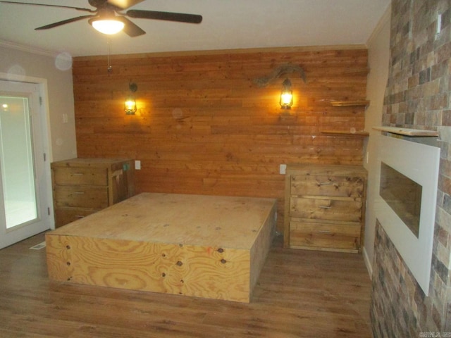 13 Cevico Ln, Hot Springs Village, AR 71909 - unfurnished bedroom with wooden walls, a fireplace, wood finished floors, crown molding, and a ceiling fan