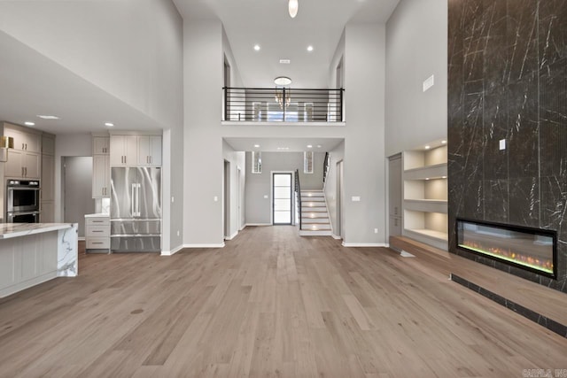 22 Abington Ct, Little Rock, AR 72223 - unfurnished living room featuring a towering ceiling, light wood-style flooring, baseboards, stairway, and recessed lighting