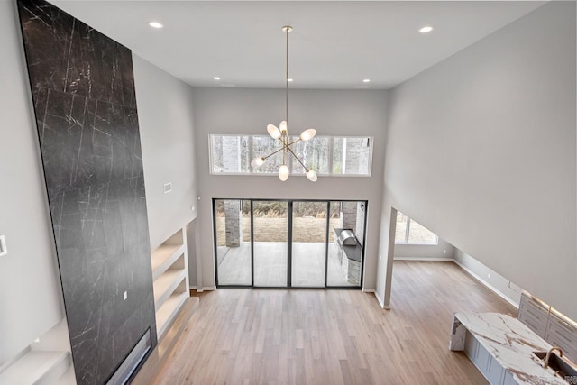 22 Abington Ct, Little Rock, AR 72223 - unfurnished living room with a chandelier, wood finished floors, recessed lighting, baseboards, and a towering ceiling