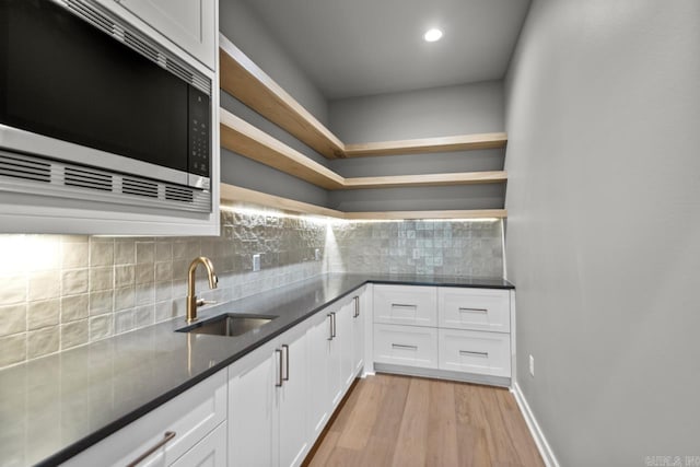 22 Abington Ct, Little Rock, AR 72223 - kitchen featuring stainless steel microwave, a sink, open shelves, light wood-style floors, and white cabinetry