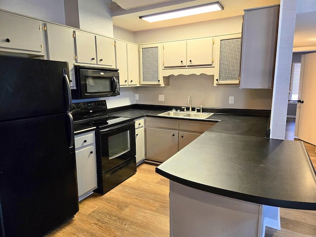 2715 Greenbriar Dr Apt B, Jonesboro, AR 72401 - kitchen featuring black appliances, a sink, a peninsula, dark countertops, and light wood-style floors