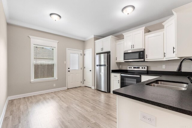 17 Woodhaven Dr, Cabot, AR 72023 - kitchen with stainless steel appliances, a sink, dark countertops, white cabinets, and light wood finished floors
