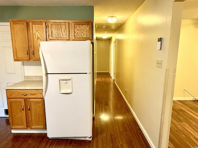 9925 Dublin Dr, Shannon Hills, AR 72103 - kitchen with freestanding refrigerator, dark wood-style flooring, brown cabinetry, and light countertops