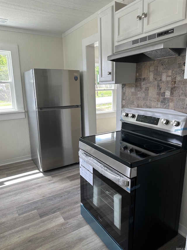 611 N Main St, Malvern, AR 72104 - kitchen featuring stainless steel appliances, under cabinet range hood, tasteful backsplash, crown molding, and light wood-style floors