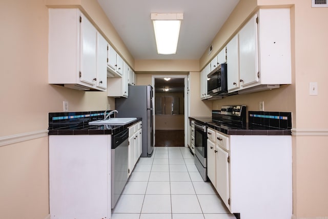 99 Kingsbridge Way, Little Rock, AR 72212 - kitchen with appliances with stainless steel finishes, white cabinetry, a sink, light tile patterned floors, and tile counters
