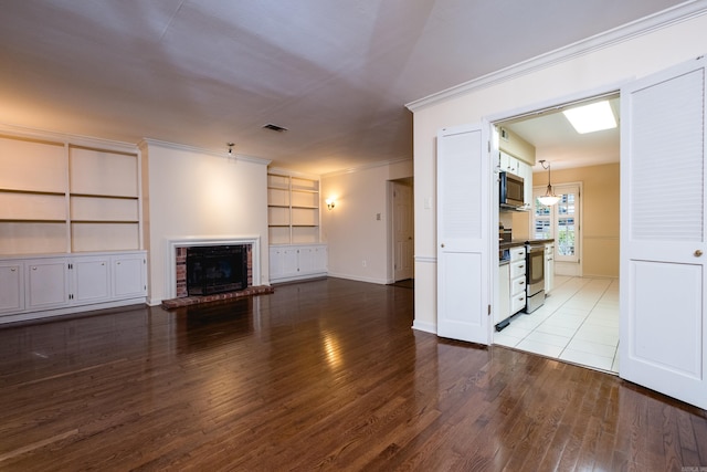 99 Kingsbridge Way, Little Rock, AR 72212 - unfurnished living room featuring wood finished floors, a brick fireplace, built in shelves, ornamental molding, and baseboards