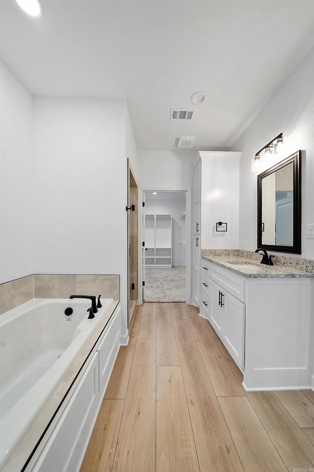 284 Shiloh, Beebe, AR 72102 - full bathroom with vanity, a garden tub, wood-type flooring, a spacious closet, and a stall shower