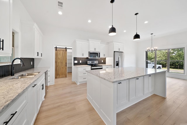 284 Shiloh, Beebe, AR 72102 - kitchen featuring stainless steel appliances, a sink, a barn door, backsplash, and light wood finished floors