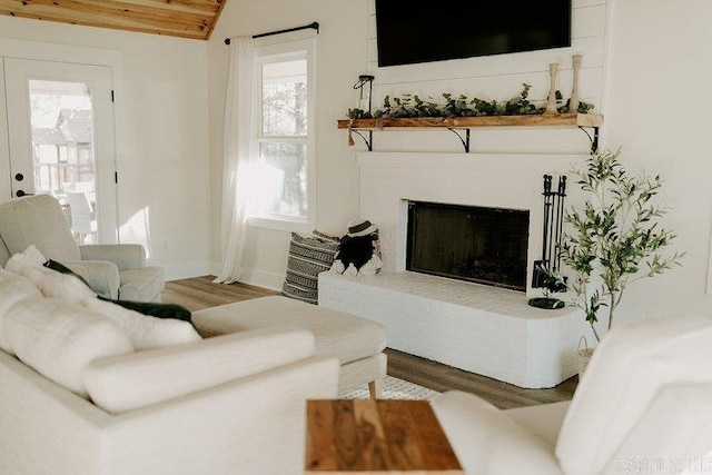 2441 Miller County 77, Doddridge, AR 71834 - living room featuring wood finished floors, baseboards, a fireplace with raised hearth, and lofted ceiling