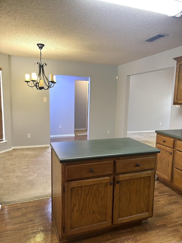 54 Redleaf Crk, Little Rock, AR 72210 - kitchen with dark countertops, a chandelier, a textured ceiling, hanging light fixtures, and a center island