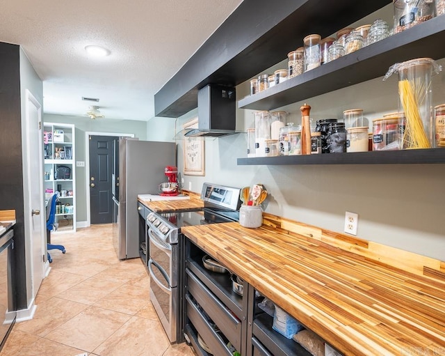 12 Wickford Ln, Little Rock, AR 72212 - kitchen featuring appliances with stainless steel finishes, wooden counters, open shelves, wall chimney exhaust hood, and light tile patterned flooring