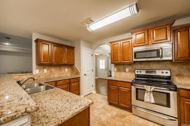 3305 Garden Club Dr, Bryant, AR 72022 - kitchen with stainless steel appliances, a sink, arched walkways, and brown cabinets