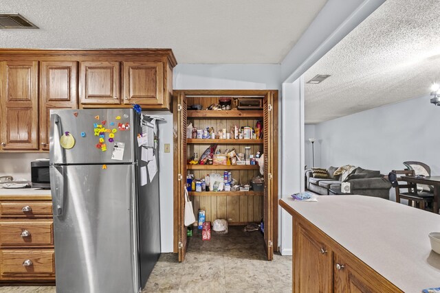 303 Pike Rd, Benton, AR 72019 - kitchen with stainless steel appliances, light countertops, brown cabinets, and a textured ceiling