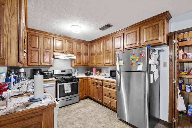 303 Pike Rd, Benton, AR 72019 - kitchen with appliances with stainless steel finishes, under cabinet range hood, brown cabinets, light countertops, and a textured ceiling