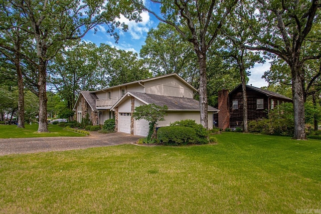 view of front of property with asphalt driveway, a garage, a front lawn, a balcony, and a chimney