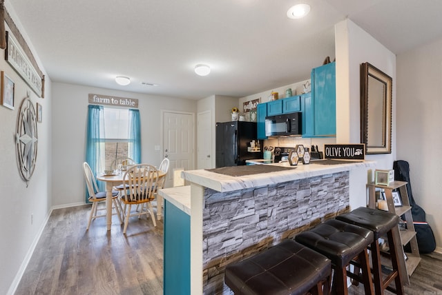 35 Summer Breeze Rd, Conway, AR 72032 - kitchen featuring black appliances, blue cabinetry, a breakfast bar area, and a peninsula