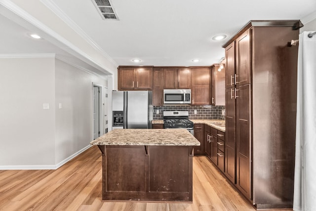 6209 Navajo Trl, North Little Rock, AR 72116 - kitchen with appliances with stainless steel finishes, a kitchen island, light wood-style flooring, crown molding, and decorative backsplash