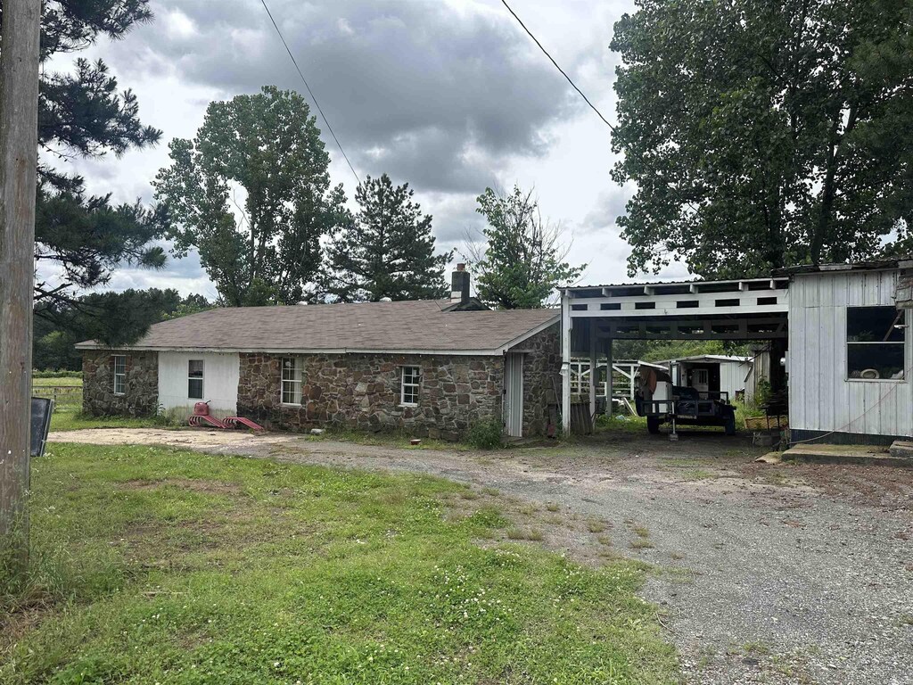 127 Windwood Country Rd, El Paso, AR 72045 - view of front of house featuring driveway, a carport, stone siding, and a chimney