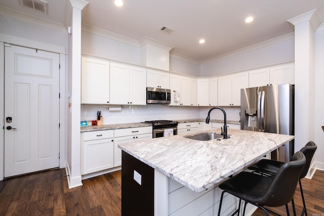 313 Parker St, North Little Rock, AR 72114 - kitchen with appliances with stainless steel finishes, a sink, ornamental molding, a kitchen bar, and light stone counters