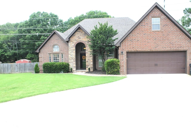 tudor home featuring concrete driveway, a shingled roof, brick siding, and stone siding