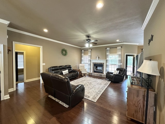 living room featuring a ceiling fan, dark wood-style flooring, recessed lighting, a glass covered fireplace, and crown molding