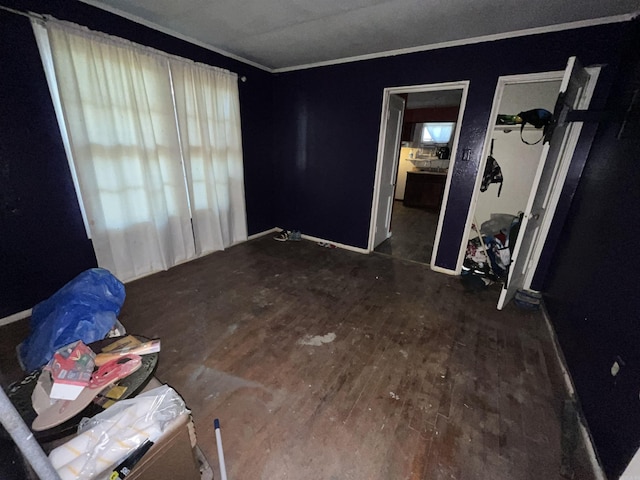 empty room featuring crown molding, wood finished floors, and baseboards