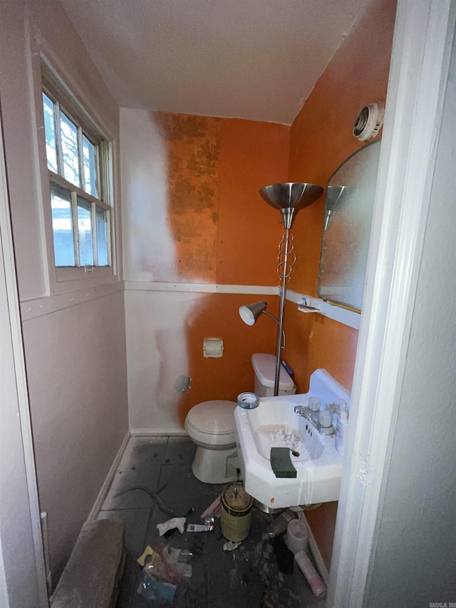 half bathroom featuring toilet, a sink, and baseboards