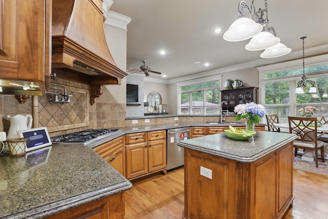 53 Maisons, Little Rock, AR 72223 - kitchen featuring appliances with stainless steel finishes, premium range hood, crown molding, a center island, and a sink