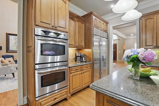 53 Maisons, Little Rock, AR 72223 - kitchen with appliances with stainless steel finishes, ornamental molding, dark stone counters, backsplash, and light wood-type flooring