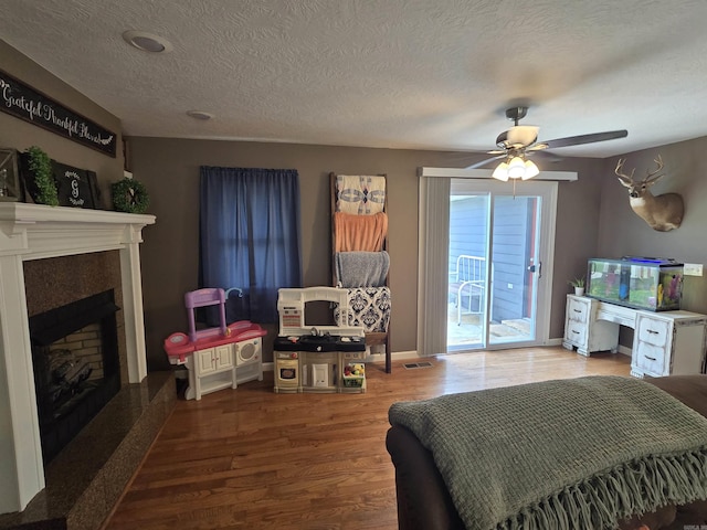 2373 W Rd, Mount Pleasant, AR 72561 - living area featuring a fireplace with raised hearth, a ceiling fan, wood finished floors, and a textured ceiling