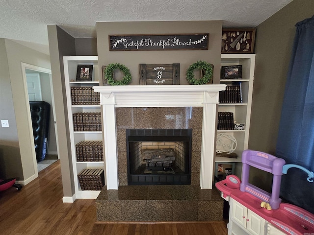 2373 W Rd, Mount Pleasant, AR 72561 - living room featuring wood finished floors, baseboards, a textured ceiling, a tiled fireplace, and built in shelves